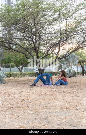 Couple profite d'un pique-nique serein au coucher du soleil sous les arbres. Banque D'Images