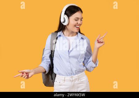 Heureuse jeune femme portant des écouteurs et dansant Banque D'Images