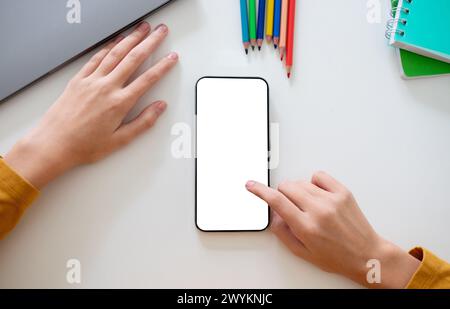 Personne utilisant un smartphone vierge posé à plat à côté de l'ordinateur portable Banque D'Images