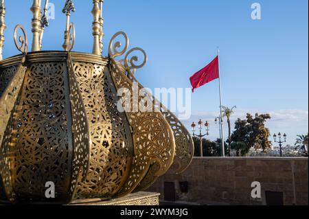 Détail des éléments décoratifs du Mausolée royal du complexe Mohammed V à Rabat, Maroc, avec le drapeau marocain ondulant en arrière-plan sur un Banque D'Images