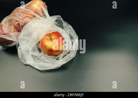 Les pommes fraîches, enveloppées dans du plastique non recyclable, mettent en évidence les défis environnementaux posés par l'utilisation excessive de plastique, soulignant la nécessité de su Banque D'Images