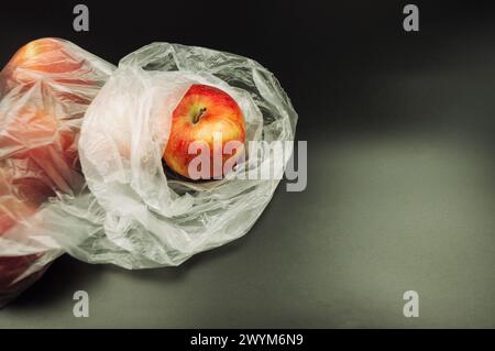 Les pommes fraîches, enveloppées dans du plastique non recyclable, mettent en évidence les défis environnementaux posés par l'utilisation excessive de plastique, soulignant la nécessité de su Banque D'Images