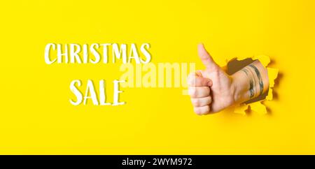 Une main donnant un pouce vers le haut avec les mots vente de Noël écrit en dessous. L'image a une ambiance positive et festive, car il s'agit d'un geste du pouce vers le haut Banque D'Images