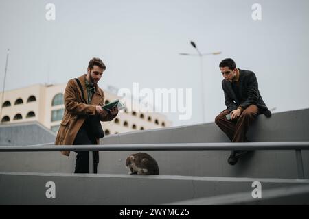 Deux hommes d'affaires utilisant la technologie tout en interagissant à l'extérieur par une journée nuageuse Banque D'Images