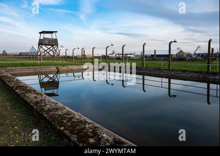 Auschwitz, Pologne, 21 mars 2024 - clôtures électriques reflétant dans une piscine d'eau du camp de concentration Banque D'Images