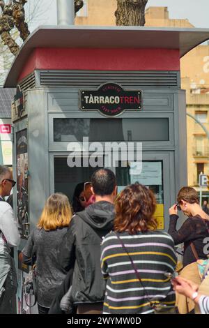 Tarragone, Espagne - 7 avril 2024 : les citoyens formant une file d'attente ordonnée pour acheter des billets à la billetterie Tarraco Tren, avec un fond urbain qui re Banque D'Images