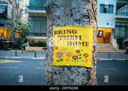 Tel Aviv, Israël. 11 mars 2024. Un morceau de tricot agrafé à un arbre dit "ramenez-les à la maison" la fontaine de la place Dizengoff est devenue l'un des endroits à tel Aviv où les gens peuvent créer des mémoriaux de fortune pour les personnes tuées et enlevées lors de l'attaque du 7 octobre 2023 par le Hamas. (Photo de Syndi Pilar/SOPA images/SIPA USA) crédit : SIPA USA/Alamy Live News Banque D'Images