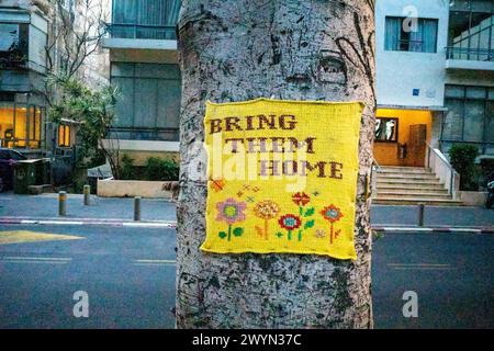 Tel Aviv, Israël. 11 mars 2024. Un morceau de tricot agrafé à un arbre indique ''ramenez-les à la maison'' la fontaine de la place Dizengoff est devenue l'un des endroits à tel Aviv où les gens peuvent créer des mémoriaux de fortune pour les personnes tuées et enlevées lors de l'attaque du 7 octobre 2023 par le Hamas. (Crédit image : © Syndi Pilar/SOPA images via ZUMA Press Wire) USAGE ÉDITORIAL SEULEMENT! Non destiné à UN USAGE commercial ! Banque D'Images