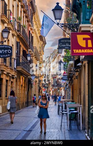 Turistas paseando en la parte Vieja, Donostia, San Sebastián, Gipuzkoa, País Vasco, España, Europa, Adentrarse en la parte Vieja es conocer el verdadero centro social de Donostia, sus calles empedradas como la del 31 de Agosto, que conmemora el incendio ese día de 1813, están llenas de bares para disfrutar de los mejores pintxos de la ciudad, y sus edificios emblemáticos como la Basílica de Santa María del Coro y la iglesia de San Vicente son de gran atractivo e interés,. Banque D'Images