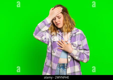 Jeune femme caucasienne malsaine présentant des symptômes de grippe saisonnière couvrant la tête avec la main, se sentant malade, allergie, fièvre ou infection virale. Unwell malade Girl isolé sur fond de clé chroma vert Banque D'Images