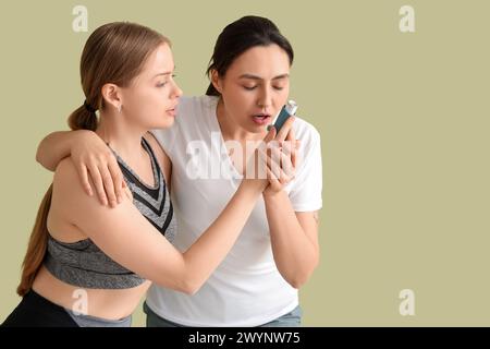 Entraîneur féminin donnant l'inhalateur à la femme avec la crise d'asthme sur fond vert Banque D'Images