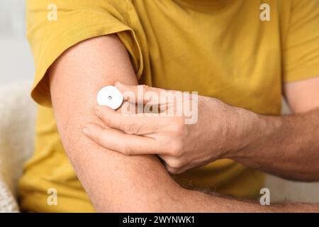 Homme senior avec capteur de glucose pour mesurer le taux de sucre dans le sang à la maison, gros plan. Concept de diabète Banque D'Images