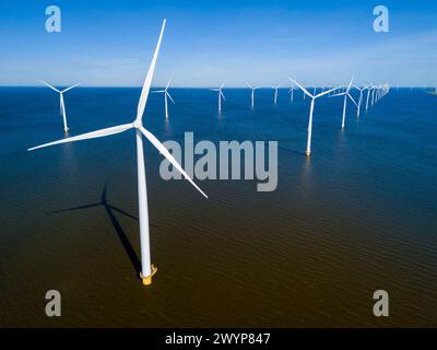 Un groupe de moulins à vent flotte gracieusement dans la région néerlandaise de Flevoland pendant la saison vibrante du printemps. drone vue aérienne des éoliennes énergie verte dans l'océan bleu Banque D'Images