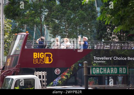 Les touristes assis sur Big bus Tour Joy Ride, sur le toit ouvert, regardant, expérimentant et prenant des photos des monuments à Orchard Road. Singapour. Banque D'Images