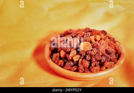 Bouquet de raisins secs dans un bol sur fond coloré, fruits de raisin séchés mangeant crus ou utilisés en cuisine Banque D'Images