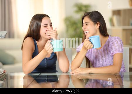 Femme parlant et riant cachant la bouche avec sa main à la maison Banque D'Images