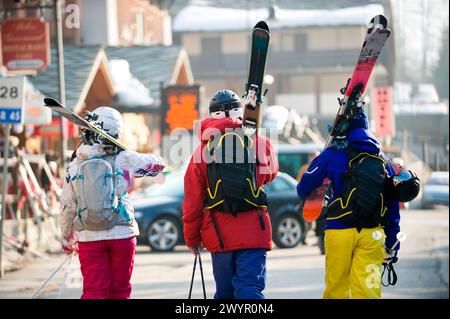 Trois skieurs marchant dans la rue dans le village italien Champoluc en Italie. Banque D'Images