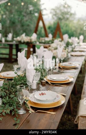 Table de mariage extérieure avec verdure luxuriante et détails dorés Banque D'Images