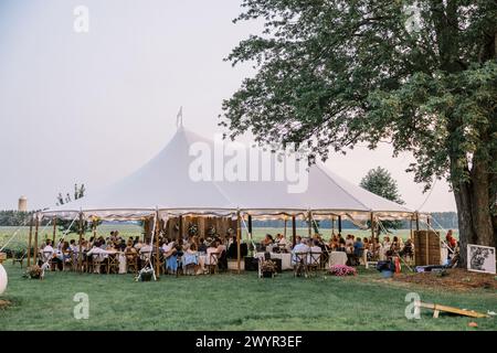 Réception de mariage en plein air sous une élégante tente au crépuscule Banque D'Images