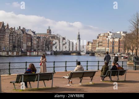 Les gens sur un banc profitant de la journée ensoleillée dans le centre historique d'Amsterdam. Banque D'Images