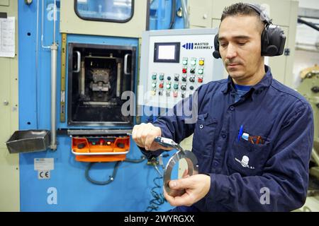 Travailleur mesurant avec pied à coulisse. ECROU de blocage. Usinage par transfert. Indecober usiné. Usinage de pièces de précision en série. Industrie automobile. Berriz. Bizkaia. Pays Basque. Espagne. Banque D'Images