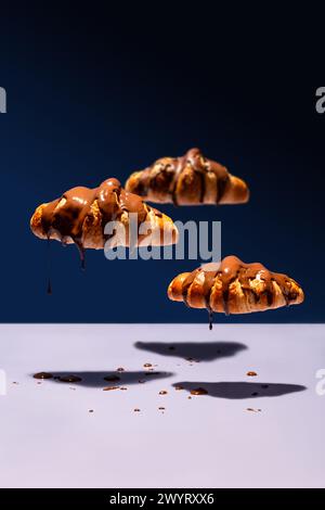 Nuages de croissants recouverts de chocolat flottant et dégouttant sur fond bleu Banque D'Images