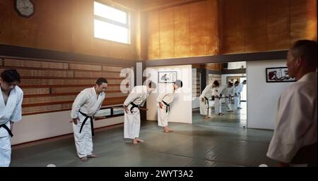 Étudiants japonais, arc ou sensei en dojo pour commencer la pratique de l'aïkido, la discipline ou l'éducation d'autodéfense. Maître ceinture noire, les gens apprennent le respect ou Banque D'Images