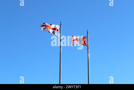 Drapeaux canadien et montréalais agitant contre le ciel bleu Banque D'Images