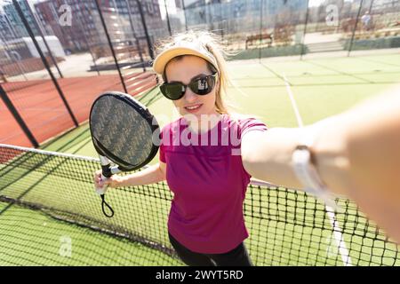 Jeune fille sportive avec raquette jouant au padel dans la cour ouverte à l'extérieur Banque D'Images