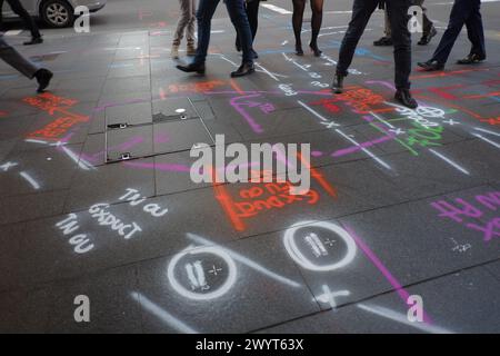 Chaussures et jambes piétons marchant sur un trottoir de couleur ardoise, marquages utilitaires multicolores peints avec des marquages violet blanc orange et vert Banque D'Images