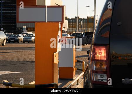 La main de l'homme prend le ticket dans la machine à tickets de contrôle à l'entrée du véhicule avec des barrières de rampe. Barrières automatiques pour parking de supermarché Banque D'Images