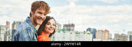 Un homme et une femme se dressent devant un horizon tentaculaire de la ville, contemplant les imposants bâtiments avec émerveillement et émerveillement Banque D'Images