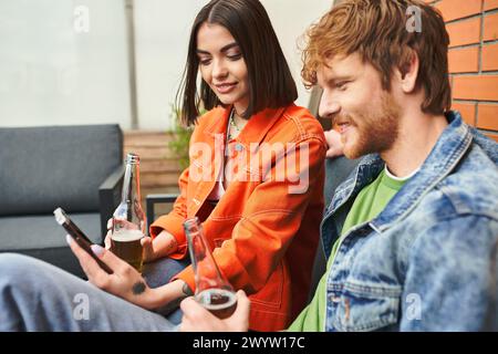 Un homme et une femme sont assis sur un canapé, pris dans un téléphone portable Banque D'Images