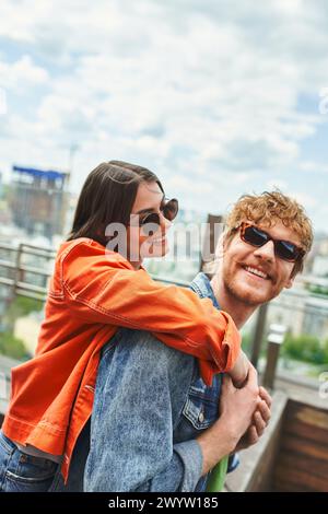 Un homme tient une femme dans une étreinte passionnée au sommet d'un bâtiment, montrant leur connexion au milieu de l'horizon urbain Banque D'Images