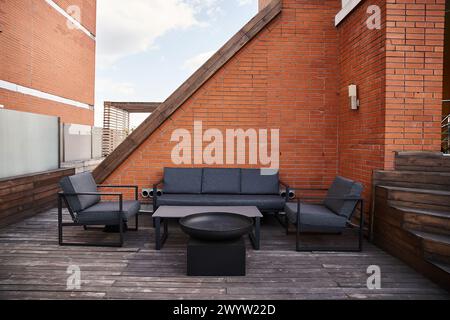 Un patio élégant avec un canapé confortable, des chaises accueillantes et une table basse élégante dans un décor de tranquillité Banque D'Images