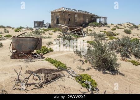 Objets rouillés gissant dans le sable près d'une maison de mineur abandonnée, préservée par l'air sec du désert, à la mine Borgenfels dans la zone interdite en Namibie. Banque D'Images