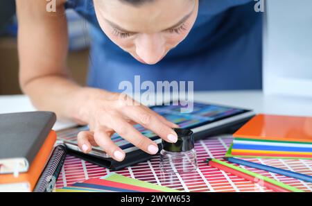 Femme designer regarde à travers la loupe à la palette de couleurs de nuances rouges Banque D'Images