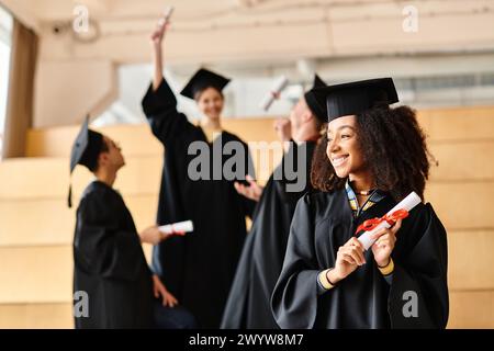 Un groupe diversifié d'étudiants en robes de graduation et mortarboards célèbrent la fin de leur voyage académique avec le sourire. Banque D'Images