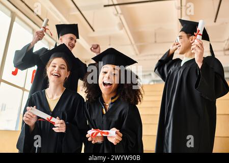 Groupe multiculturel d'étudiants célébrant leur graduation dans des robes colorées, serrant les diplômes avec des sourires et de la fierté. Banque D'Images