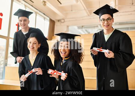 Un groupe d'étudiants divers, y compris des membres caucasiens, asiatiques et afro-américains, debout ensemble dans des robes académiques et des casquettes. Banque D'Images