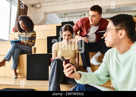 Un groupe multiculturel d'étudiants s'assoit confortablement sur un escalier moderne, s'engageant dans la conversation et la détente Banque D'Images