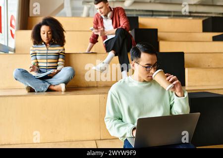 Homme asiatique assis sur les marches, utilisant un ordinateur portable à des fins d'étude Banque D'Images