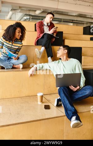 Un groupe de personnes, y compris des étudiants multiculturels et afro-américains, assis sur des gradins avec des ordinateurs portables Banque D'Images