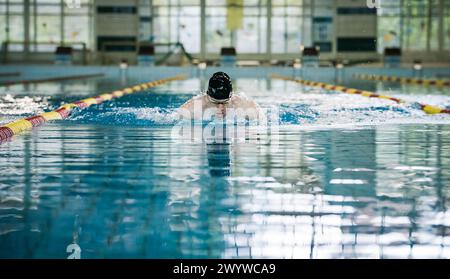 Nageur professionnel de style papillon dans la voie intérieure de la piscine pour longueurs, vue de face. Concept de réussite, de motivation et d'effort. Banque D'Images