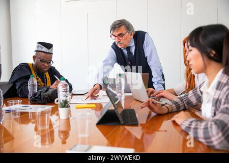 Réunion de travail dans une entreprise, le patron explique le travail aux employés, groupe multi ethnique. Banque D'Images