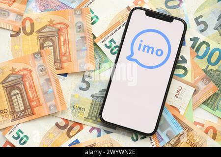 KIEV, UKRAINE - 1er AVRIL 2024 icône de messagerie IMO sur l'écran du smartphone sur de nombreuses factures d'argent en euros. Écran iPhone avec logo APP avec billets en euros en monnaie européenne Banque D'Images