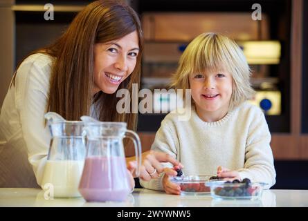 Famille dans la cuisine. La mère et le fils. L'alimentation saine. Une croissance saine. Faire des milkshakes aux fruits rouges. Banque D'Images