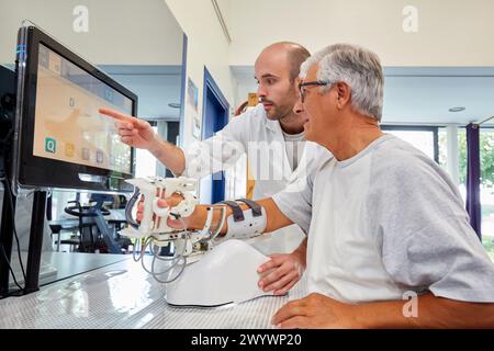 Thérapeute et patient avec robot d’assistance pour la rééducation des membres supérieurs, le robot ArmAssist permet un entraînement passif, assisté et actif du bras et de la main, permettant le traitement de la plupart des patients atteints d’AVC. Dispositif médical pour traitement neurologique. La plate-forme logicielle permet une évaluation à distance des progrès du patient et une gestion de la thérapie basée sur des jeux sérieux, qui motivent les patients à participer activement à leur rééducation et à maximiser. The Outcome, unité de technologie de la santé, Tecnalia Research & innovation, Adacen, Centre de traitement et de réadaptation des lésions cérébrales, M. Banque D'Images