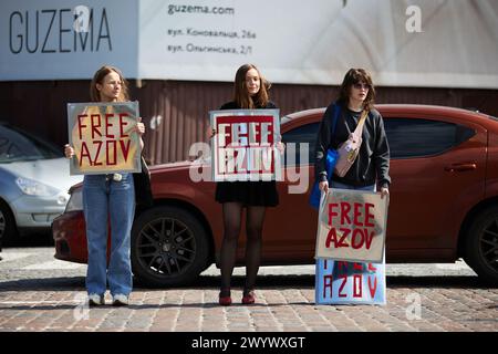 Trois jeunes filles ukrainiennes posant avec des banderoles "Free Azov" lors d'une manifestation publique pour la libération des défenseurs capturés de Marioupol et de l'usine Azovstal des prisons russes. Kiev - 7 avril 2024 Banque D'Images