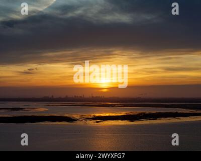 Vue en altitude du coucher de soleil sur le port de Langstone et les marais de Farlington depuis Havant. Ville de Portsmouth skyline peut être vu au loin. Banque D'Images